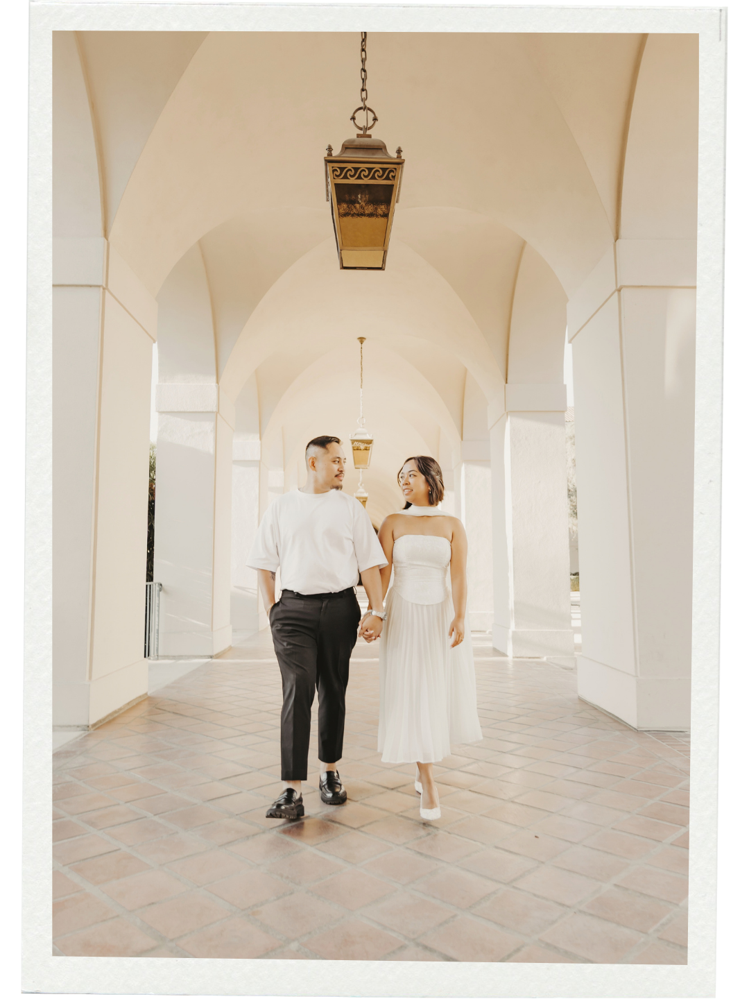 Jyselle and Kyle walking hand in hand under an archway